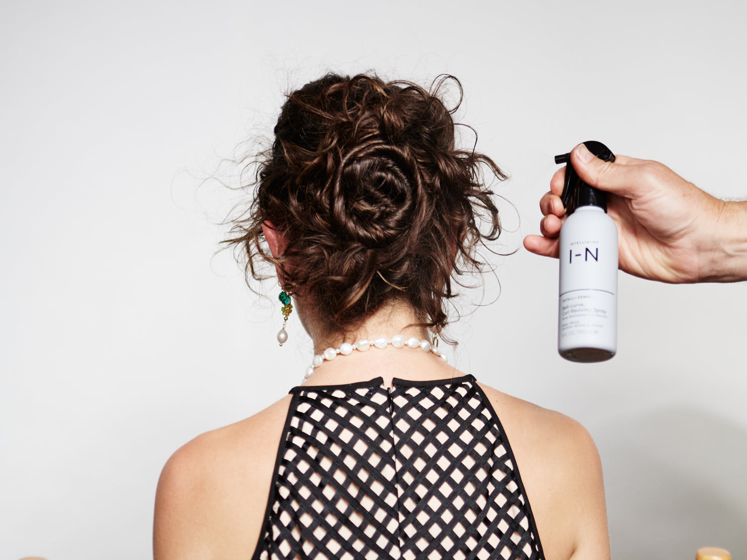Bell-curve Curl Reviving Spray being applied to curly hair
